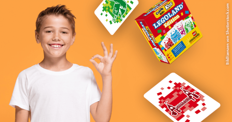 fröhlicher Junge umgeben von Karten und Schachtel mit Legoland-Branding
